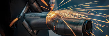 Tube laser cutting a spiral out of a round metal tube with sparks flying